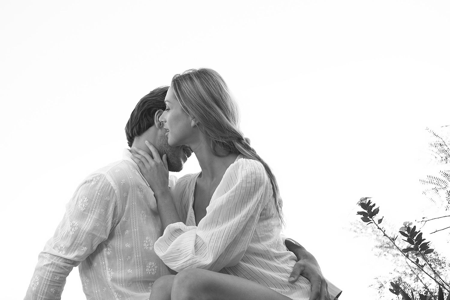 Artistic black and white engagement photos of couple in romantic seaside setting.