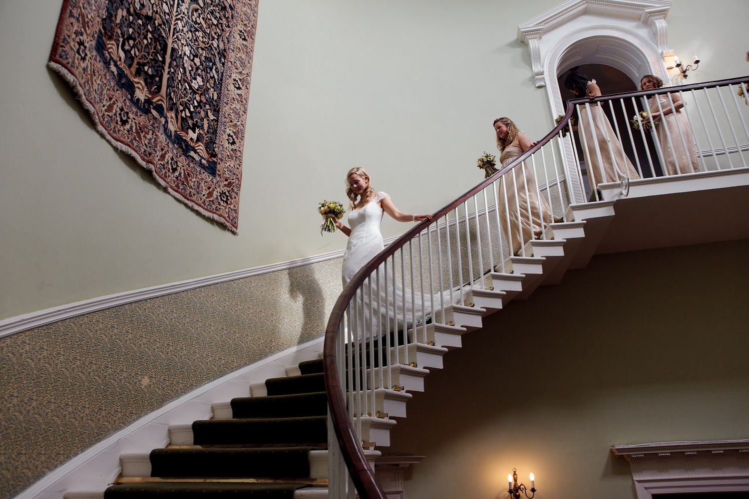 Wedding party descending grand white staircase in formal attire.