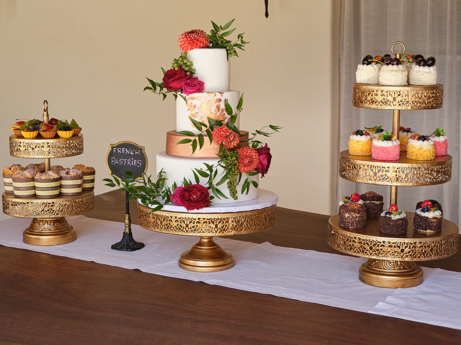 Wedding dessert display featuring gold cake stands with various treats and pastries.