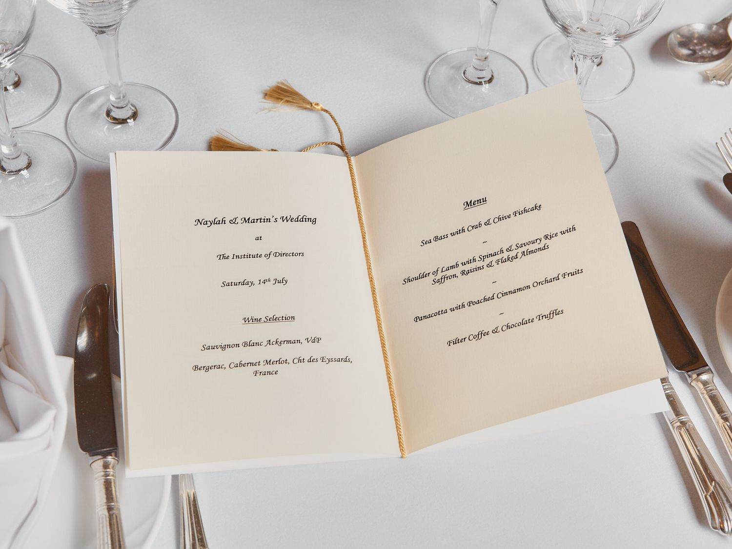 Elegant place settings with printed wedding menus at formal reception.