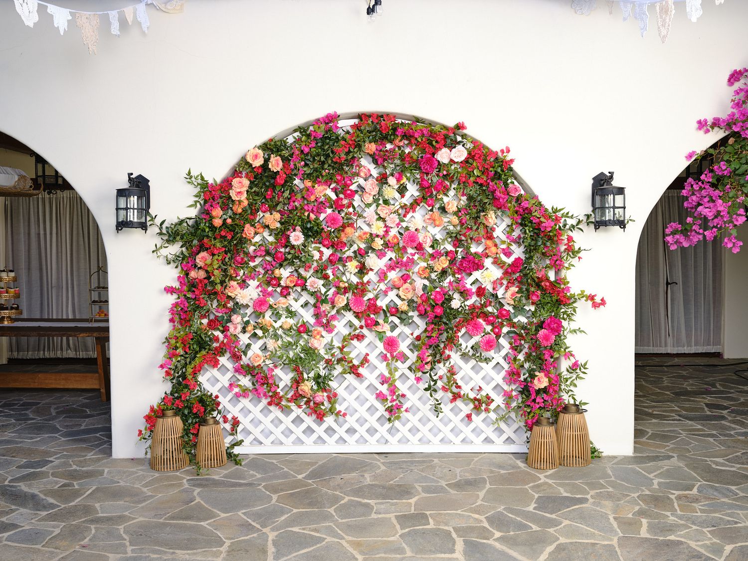 Beautiful pink floral archway adorning a white Mediterranean building entrance at wedding in LA.