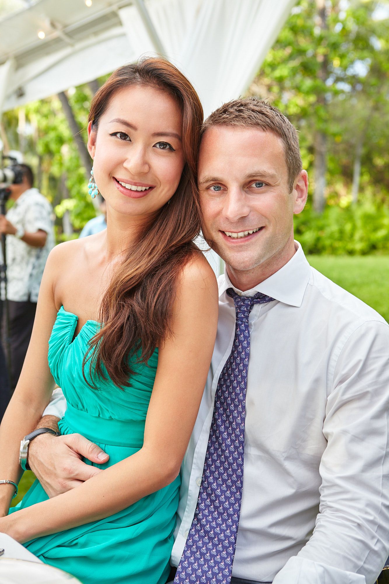 A romantic outdoor photoshoot featuring a couple in a turquoise dress and blue tie against lush greenery at a destination wedding in Hawaii.