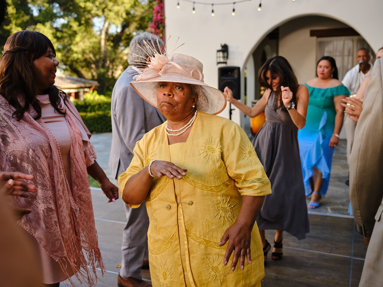Outdoor wedding celebration with guests mingling under string lights.