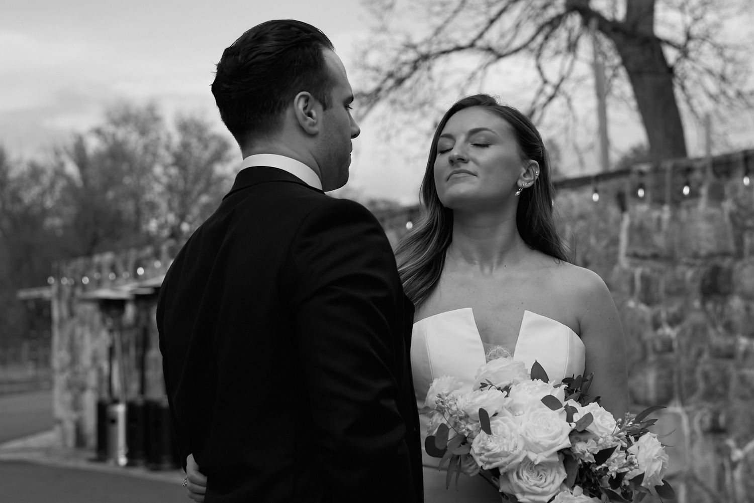 Black and white photo of bride and groom sharing an intimate moment outdoors at their wedding ceremony.