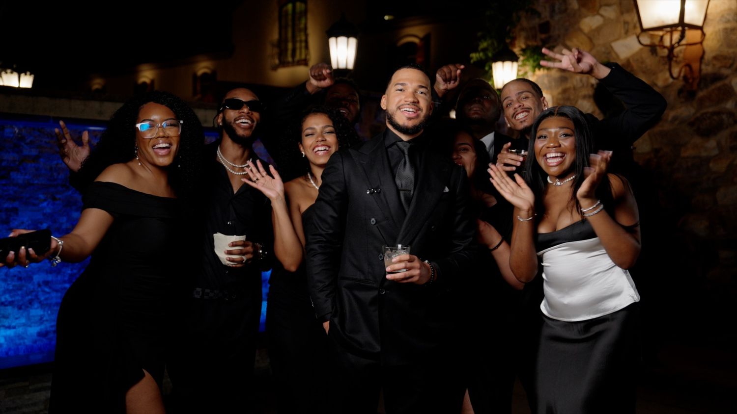 Group of friends celebrating and posing together at an elegant outdoor evening party.