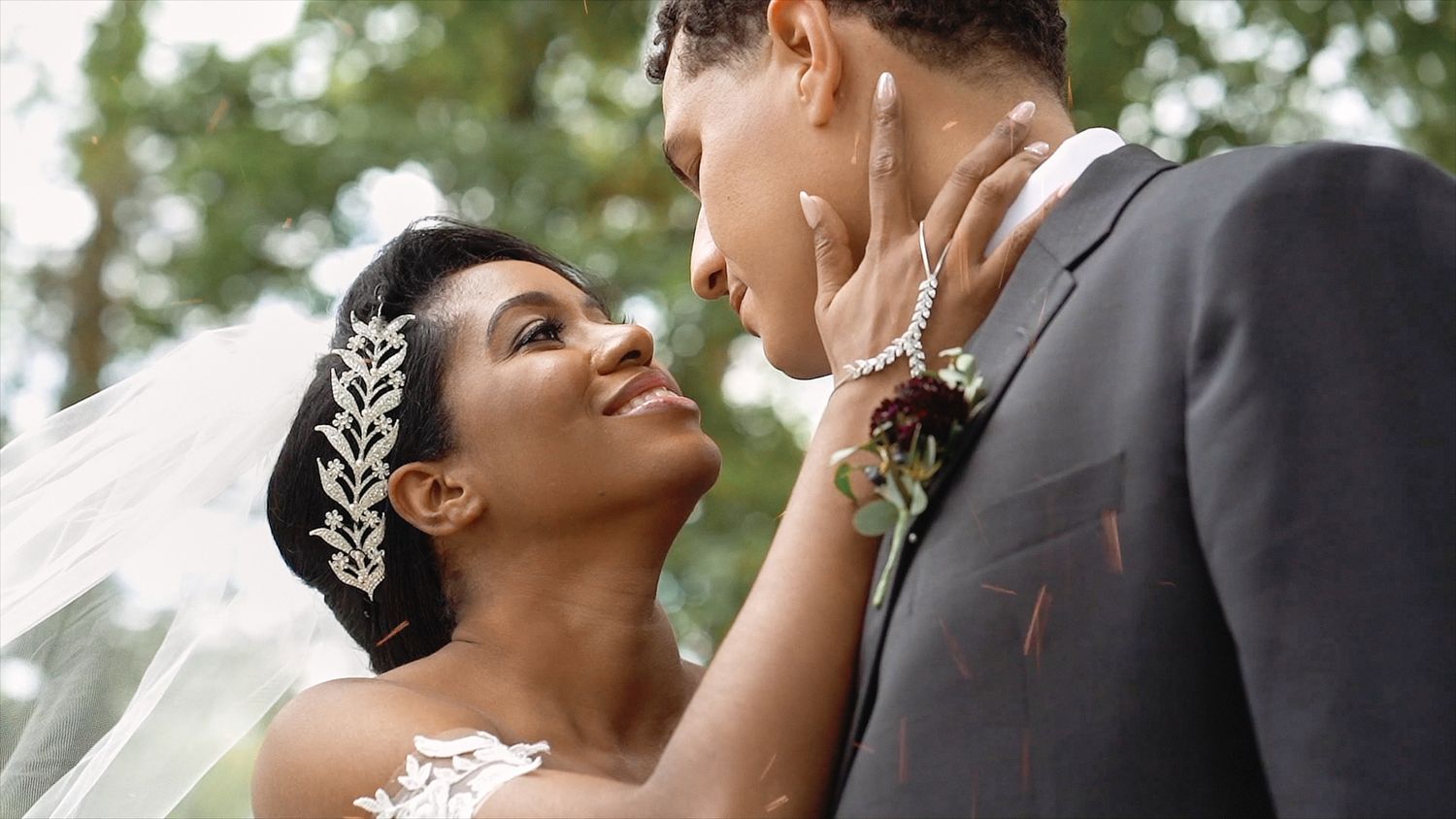 Interracial couple sharing an intimate moment outdoors under a wedding veil.