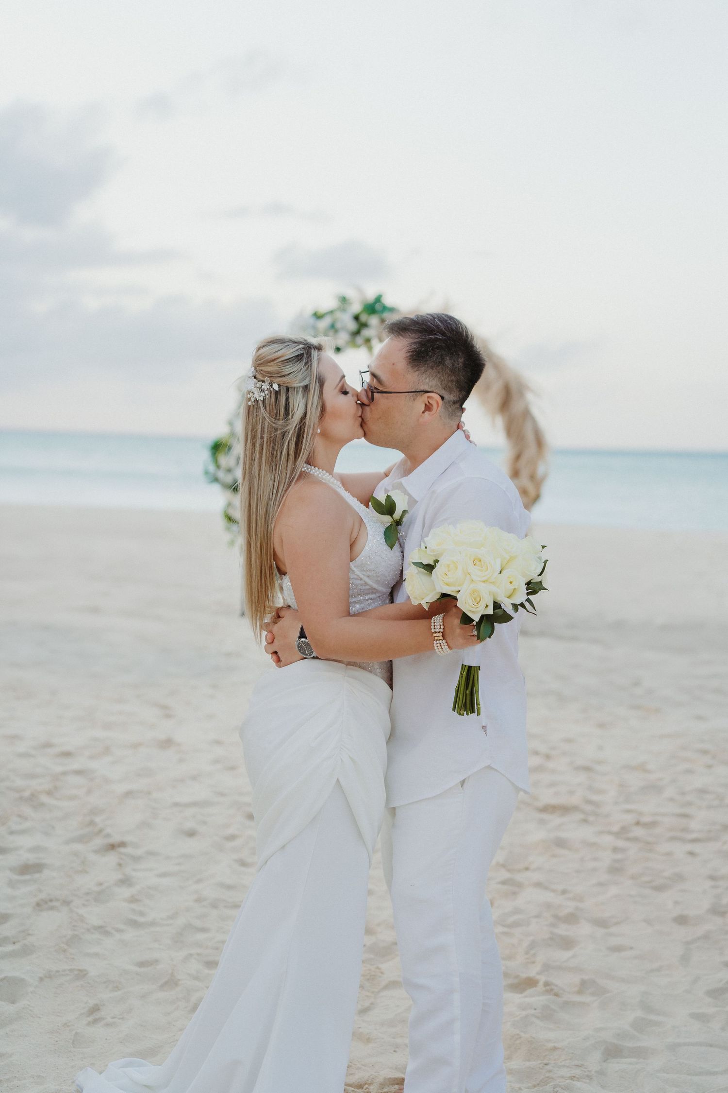 Intimate beach wedding portraits with white florals and gentle ocean breeze.