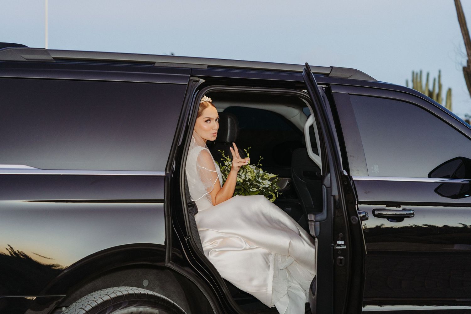 A black luxury vehicle with tinted windows parked outdoors during sunset.