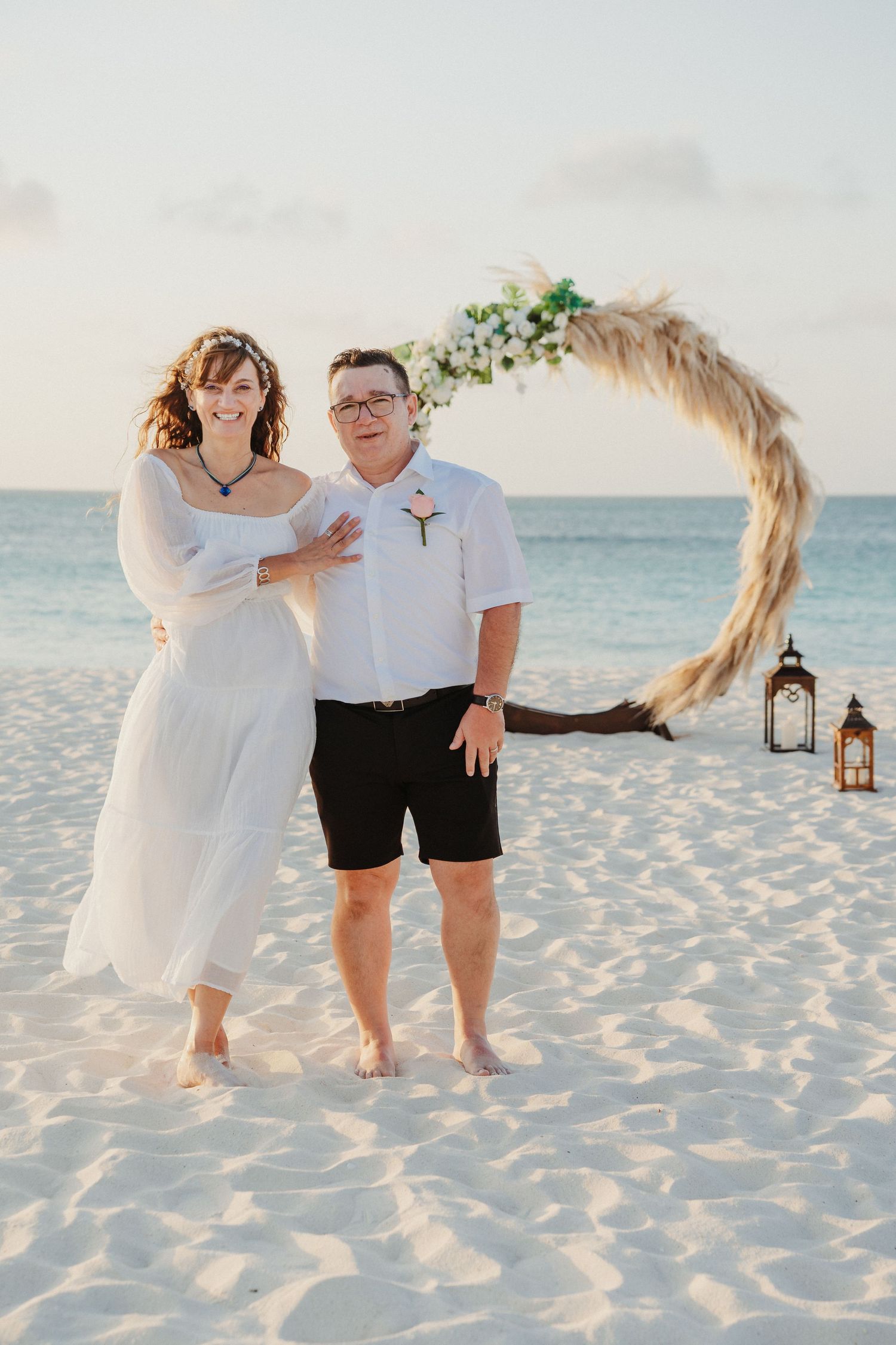 A romantic beach photoshoot at sunset with couples dancing and twirling on white sandy shores.