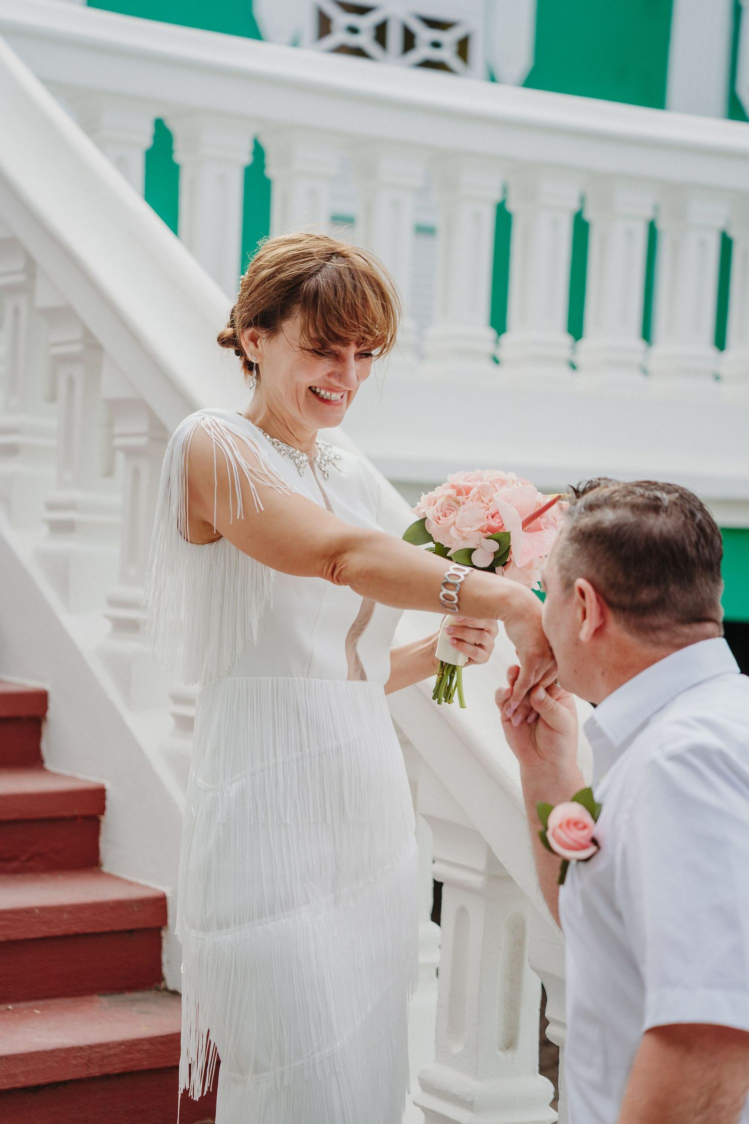 A romantic moment unfolds on white porch steps with pink flowers and green accents.