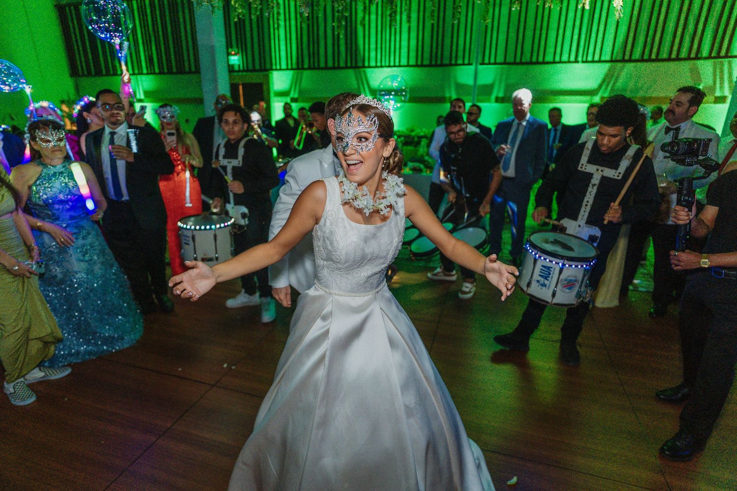 A wedding reception dance floor illuminated with green lighting as someone in a white satin gown dances joyfully.