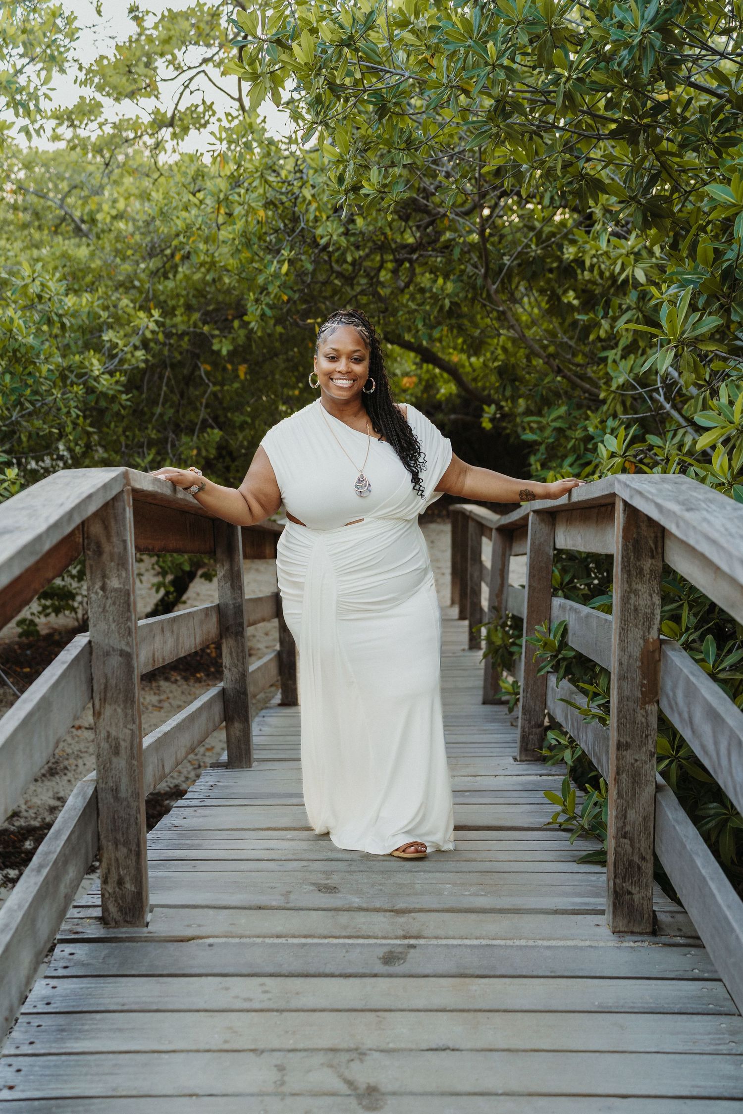 A sequence of photos showing someone in a white dress posing playfully on a wooden boardwalk surrounded by greenery.