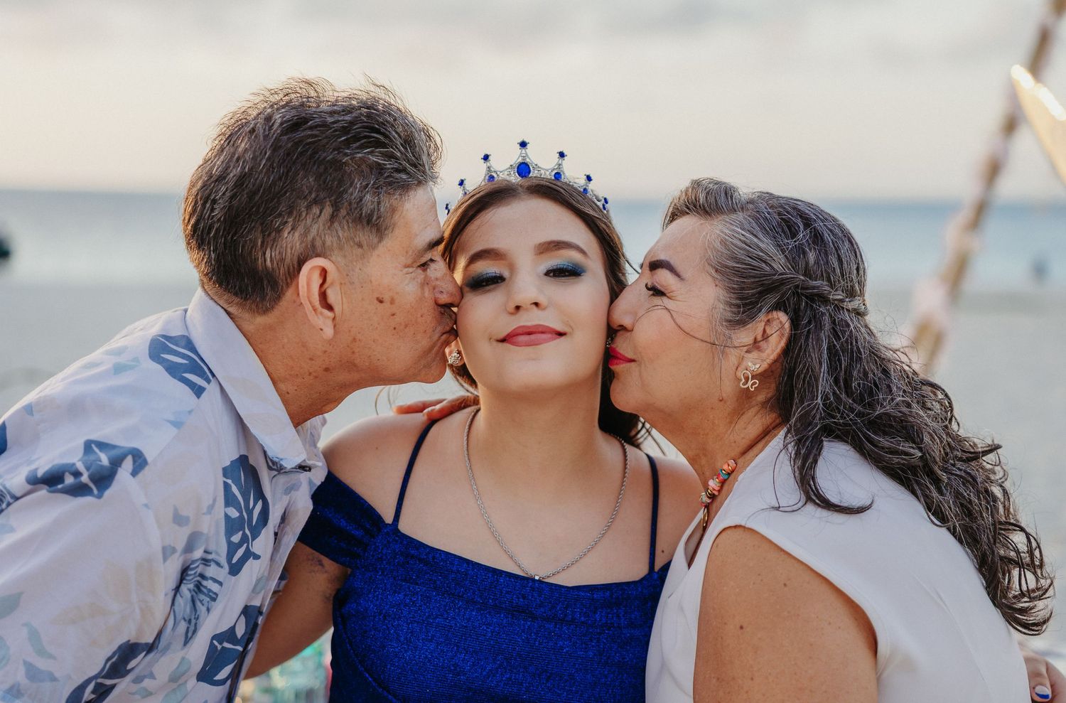 Family members sharing sweet kisses and embraces during a sunset beach photoshoot.