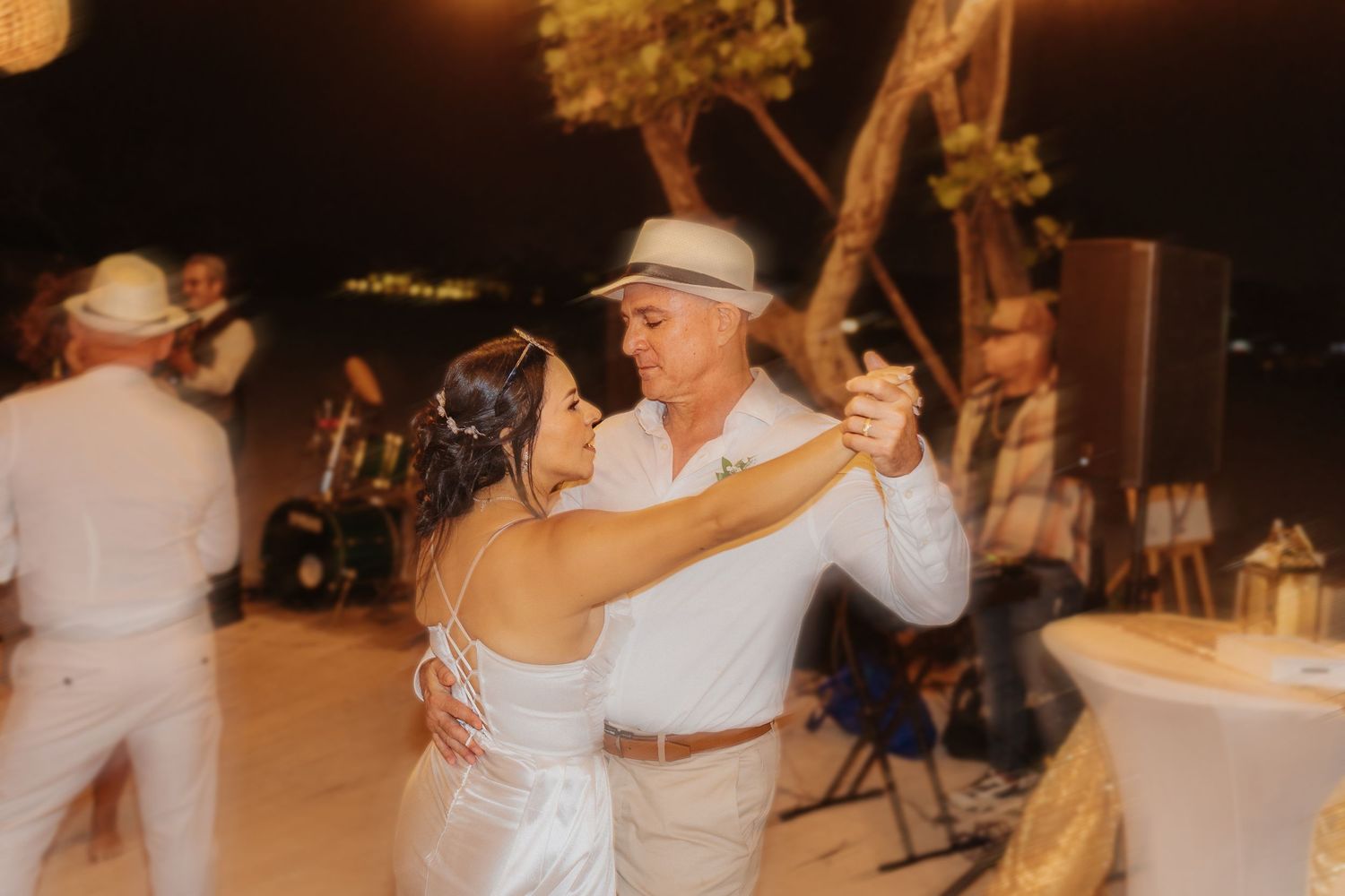 Couples dancing together at an outdoor evening wedding reception with warm lighting and festive atmosphere.