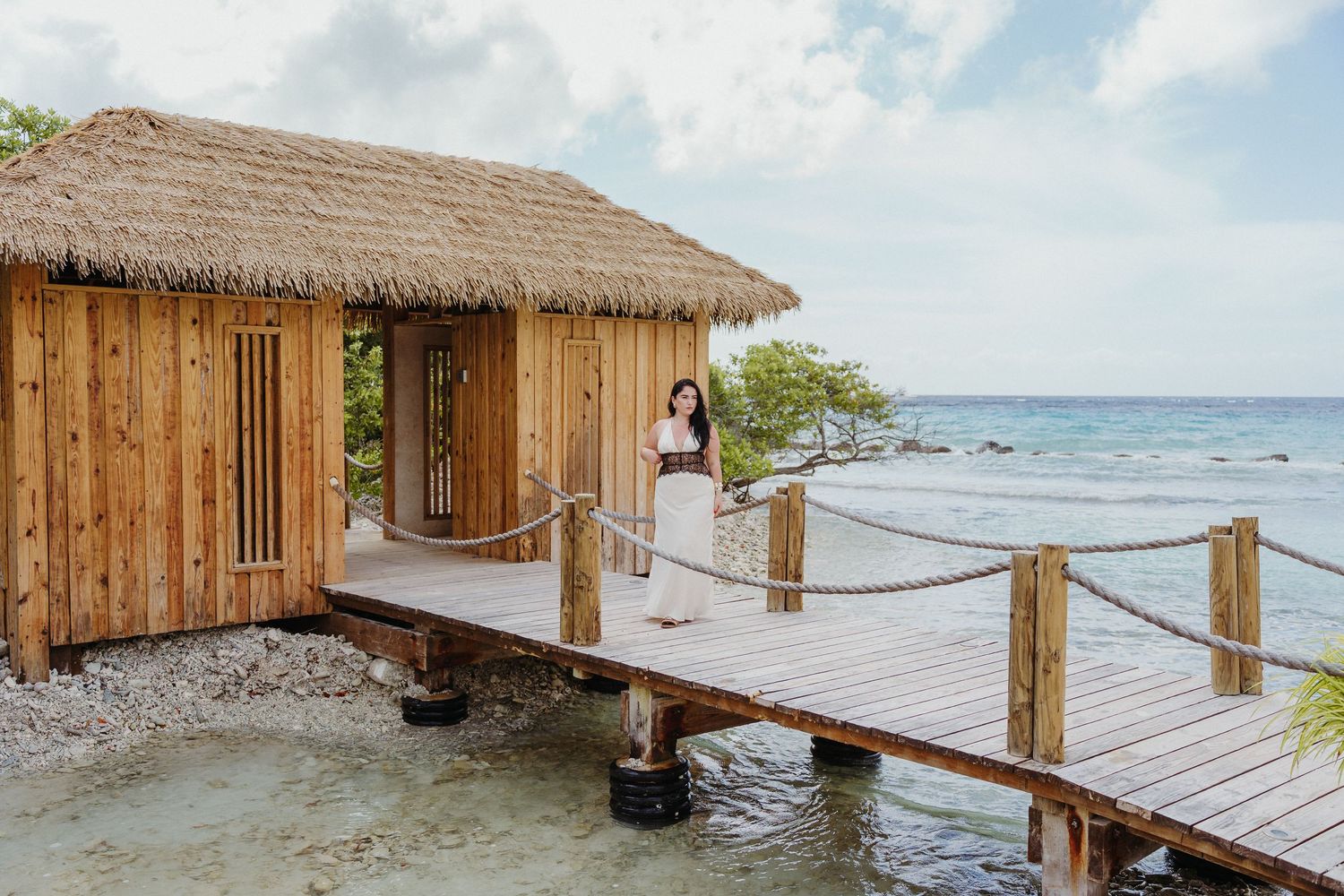 Tropical overwater bungalows with thatched roofs connected by wooden walkways extend into the calm turquoise ocean.