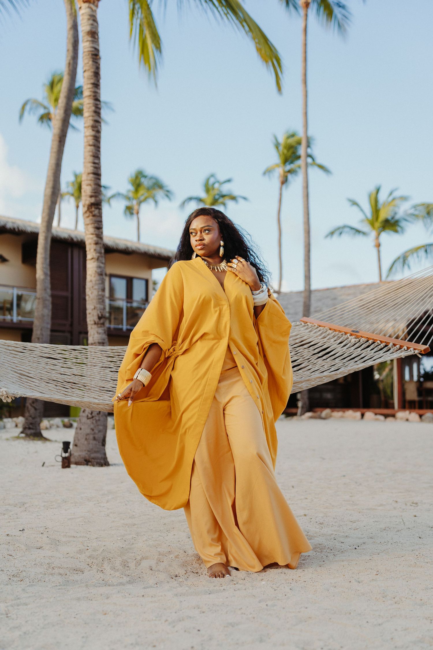A series of photos showing someone in a flowing yellow dress dancing on a tropical beach with palm trees.