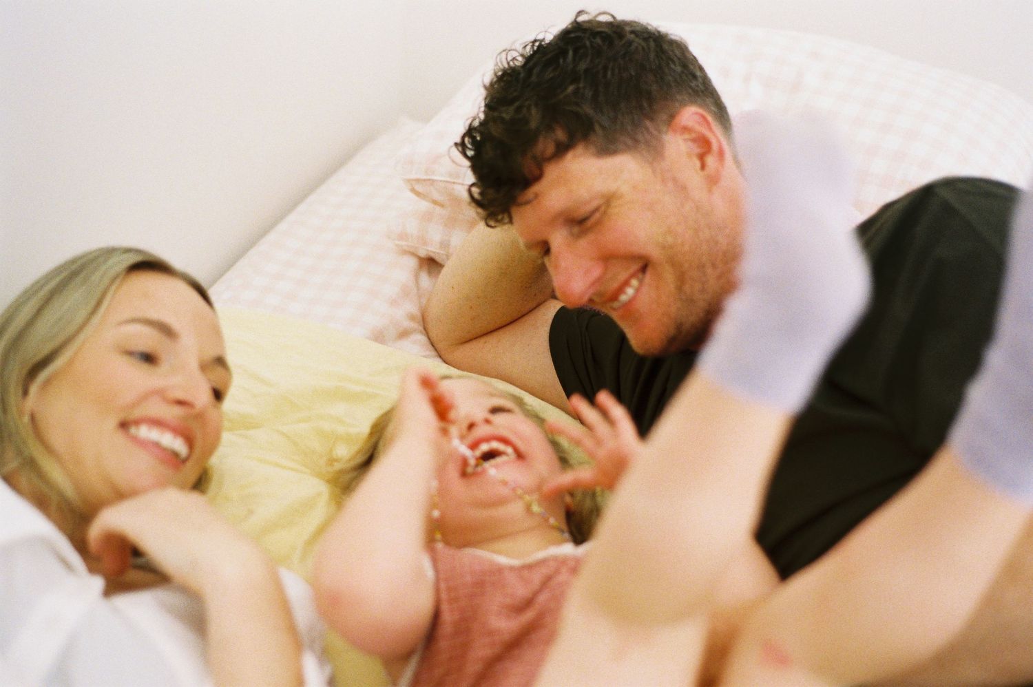 A happy family shares a joyful moment together while relaxing on a bed. Mornington Peninsula Photography