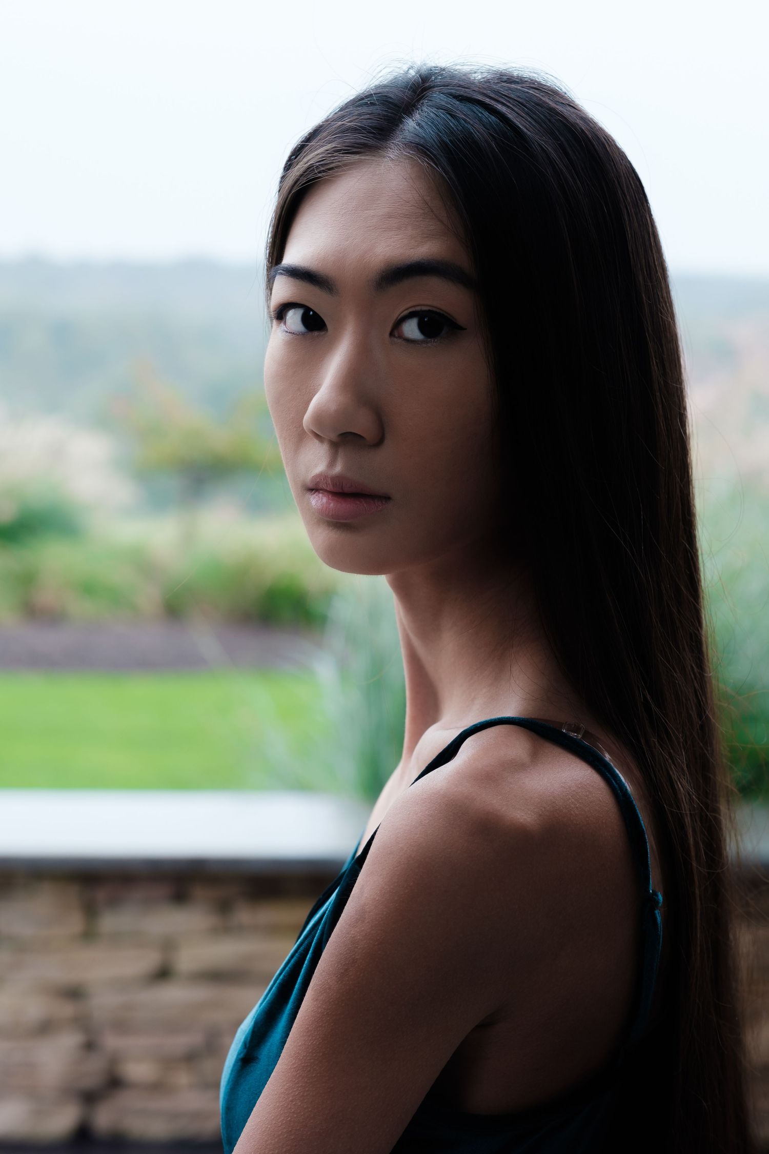 Portrait of woman in teal dress against blurred outdoor background.