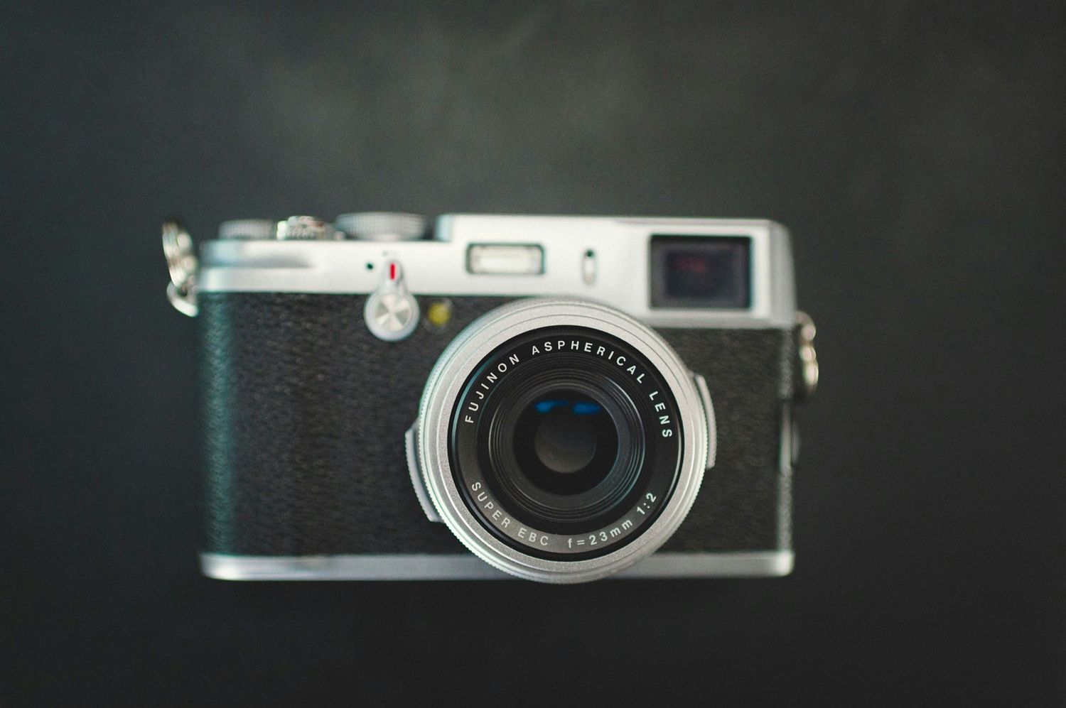 Vintage silver rangefinder camera on dark background.