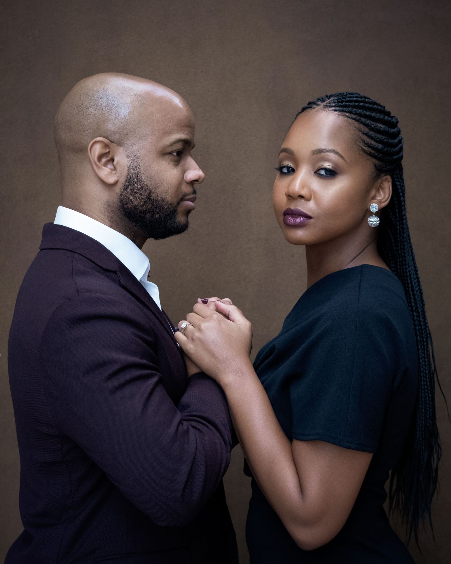 Elegant couple in black formal wear sharing tender moments in a romantic photoshoot.