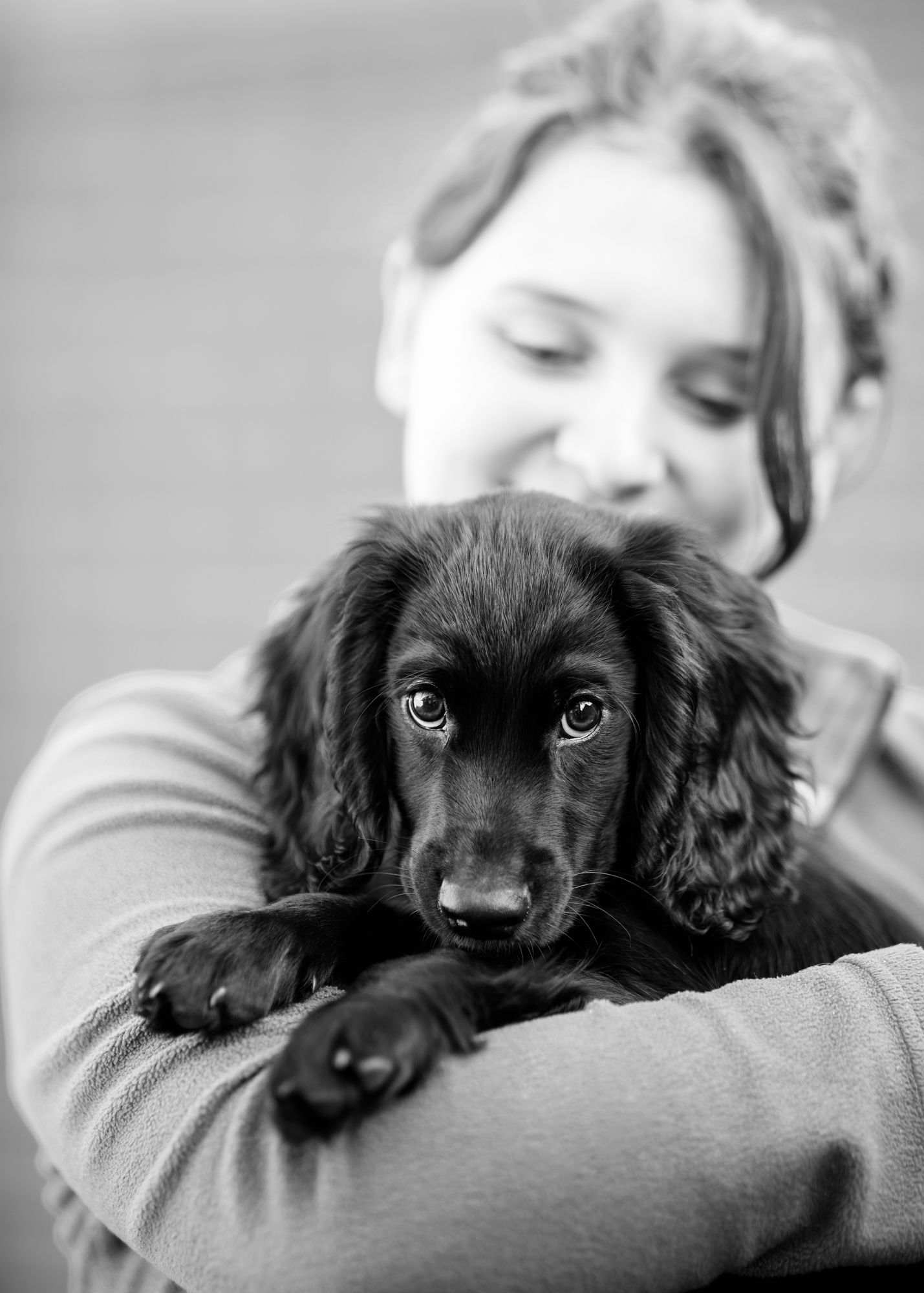 A lady holding a black puppy in her arms