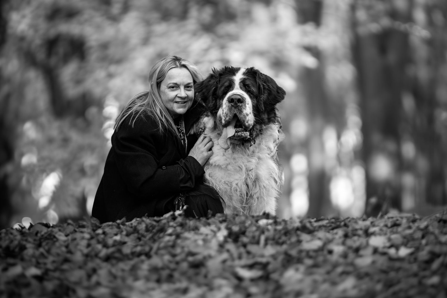 A black and white image of a lady crouched next to her Saint Bernard dog
