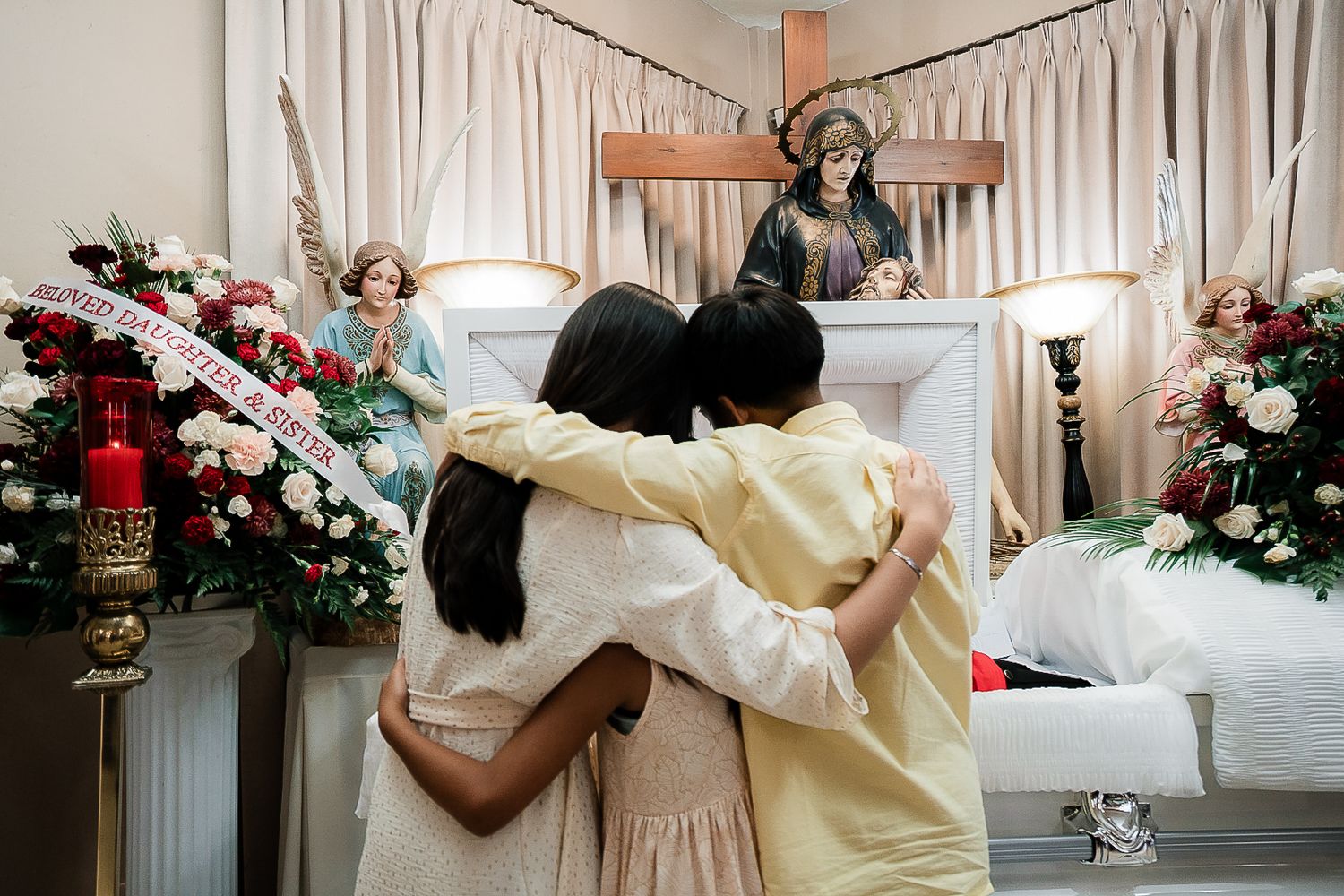 Guam funeral photographer capturing family members embracing in comfort near a casket in a chapel.