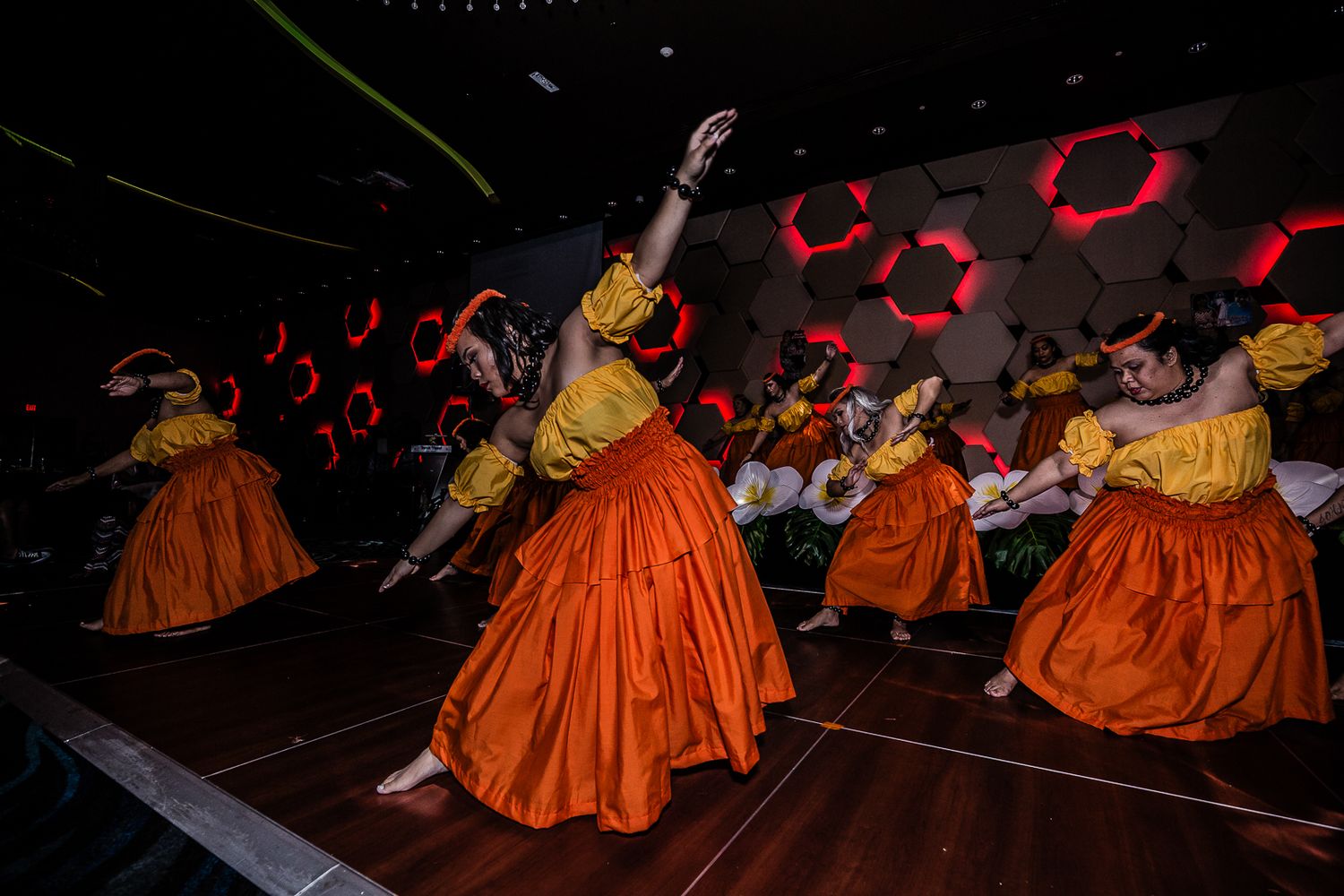 Guam event photographer capturing performers dancing on a stage with colorful red hexagon lighting.