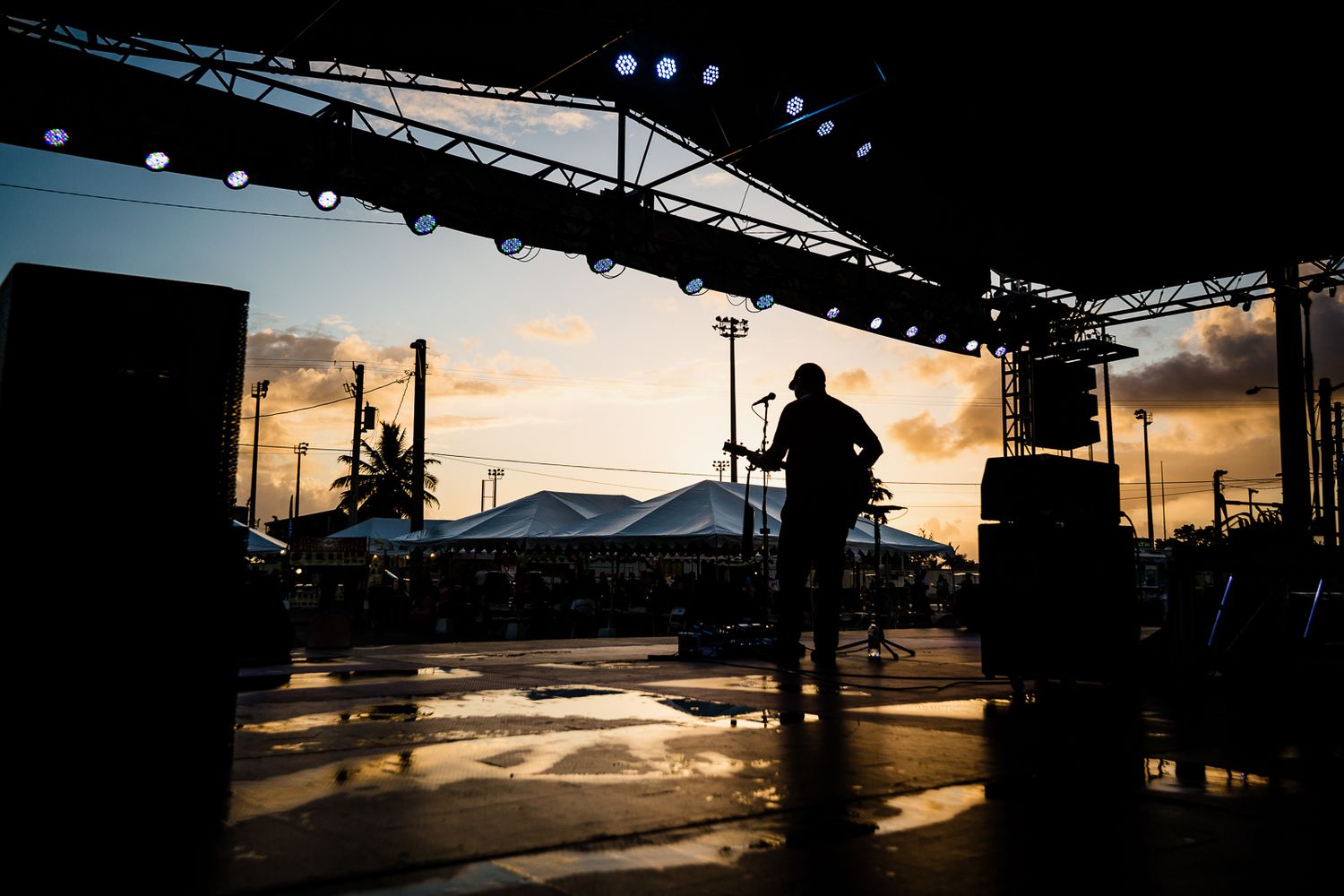 Guam event photographer capturing a silhouette of a performer on stage at sunset during an outdoor concert event.