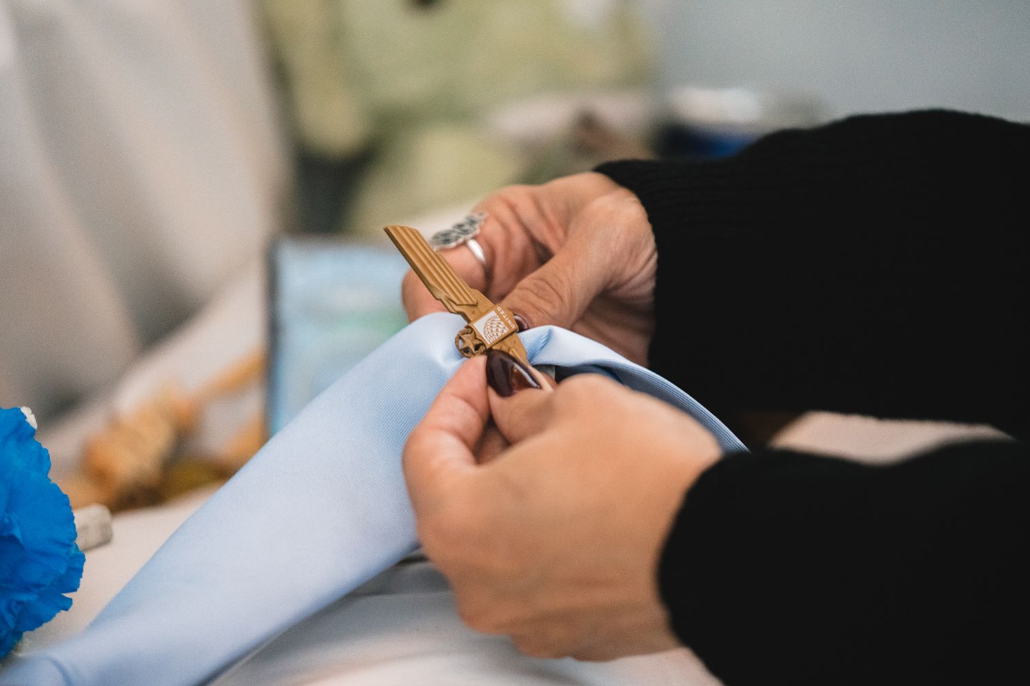 Guam funeral photographer capturing a close-up of hands pinning a decorative cross brooch onto a light blue shirt at a funeral.