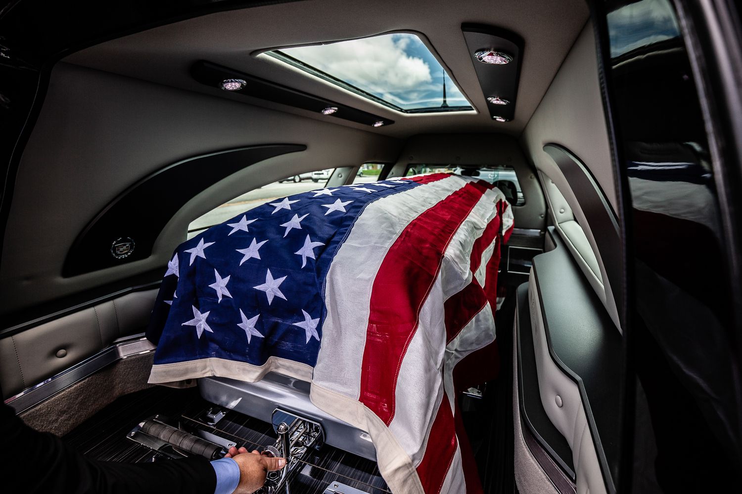 Guam funeral photographer capturing an American flag-draped casket inside a hearse during a military funeral procession.