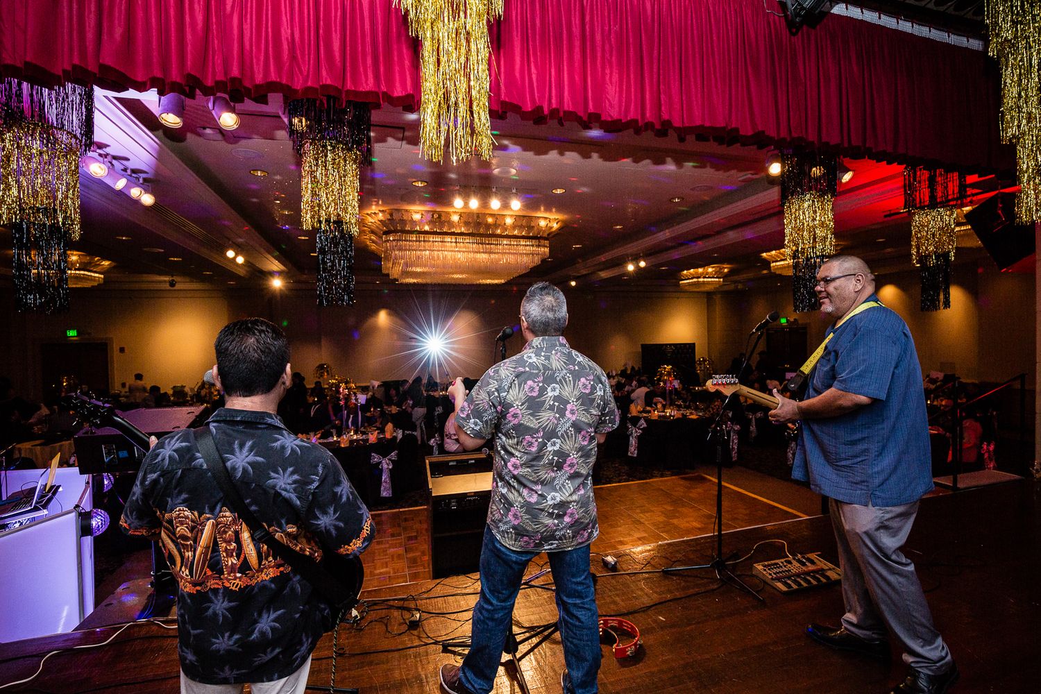 Guam event photographer capturing a live band performing on stage with red curtain backdrop at a festive indoor celebration.