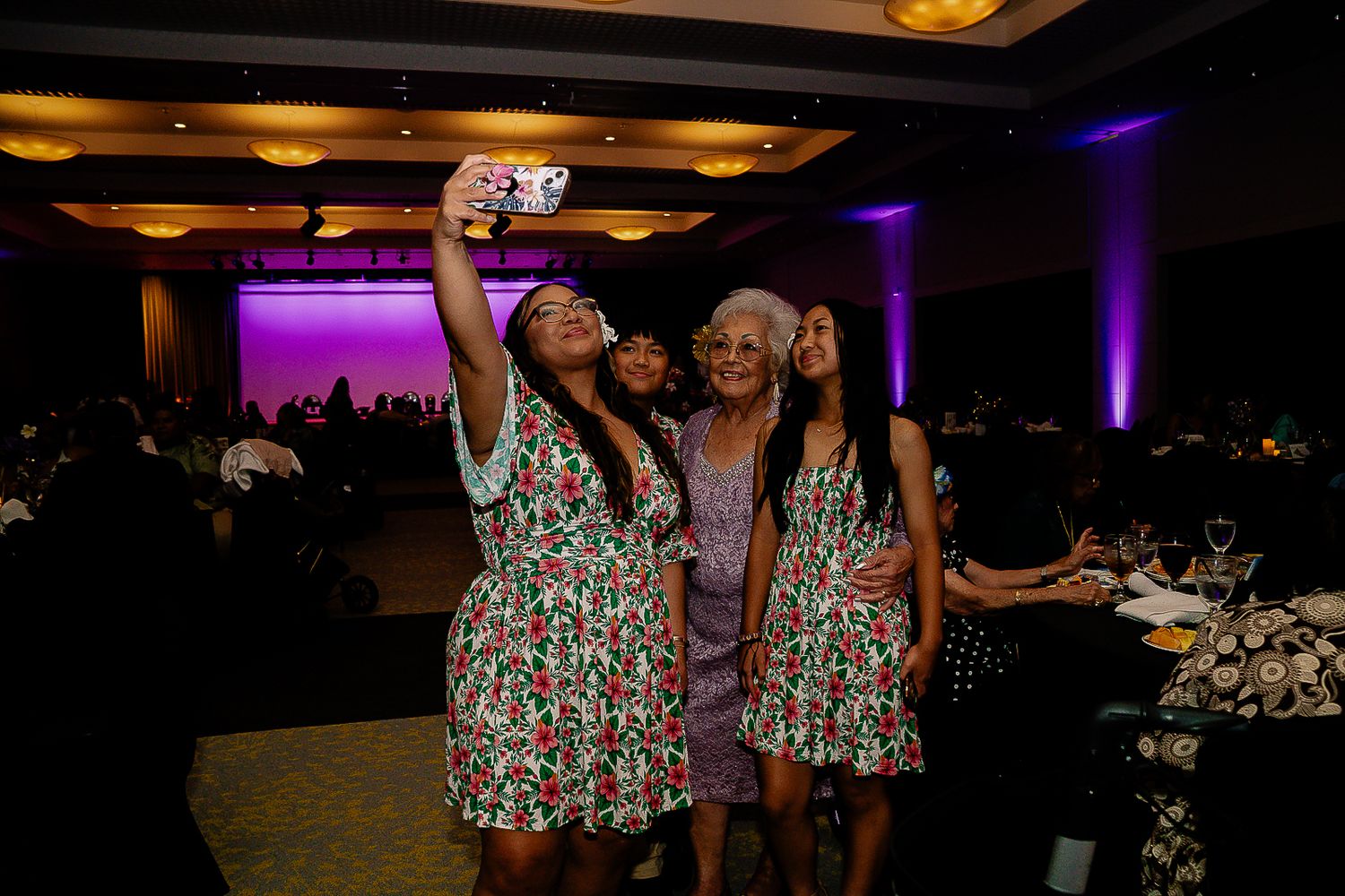 Guam event photographer capturing a group of women taking a selfie together under purple lighting at an elegant banquet hall.