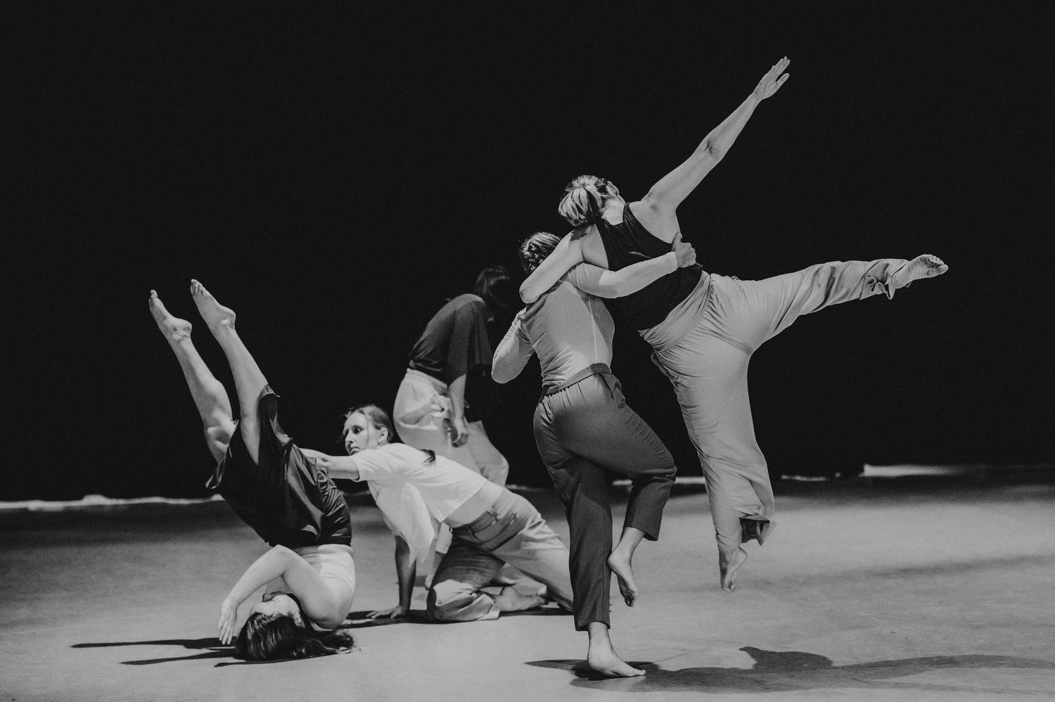 Black and white photo of modern dancers performing dynamic movements on stage.