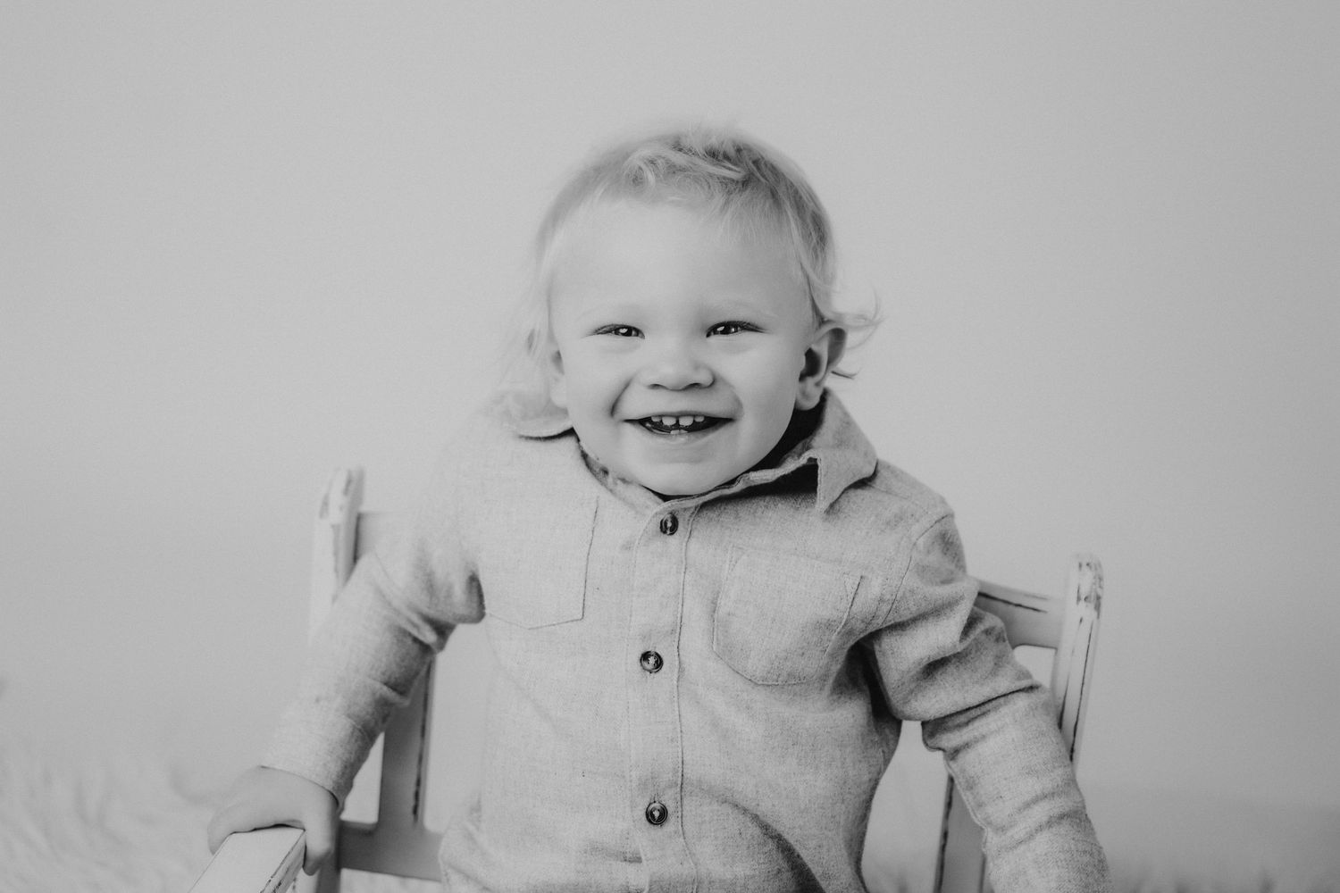 Black and white portrait of joyful toddler in buttoned shirt.