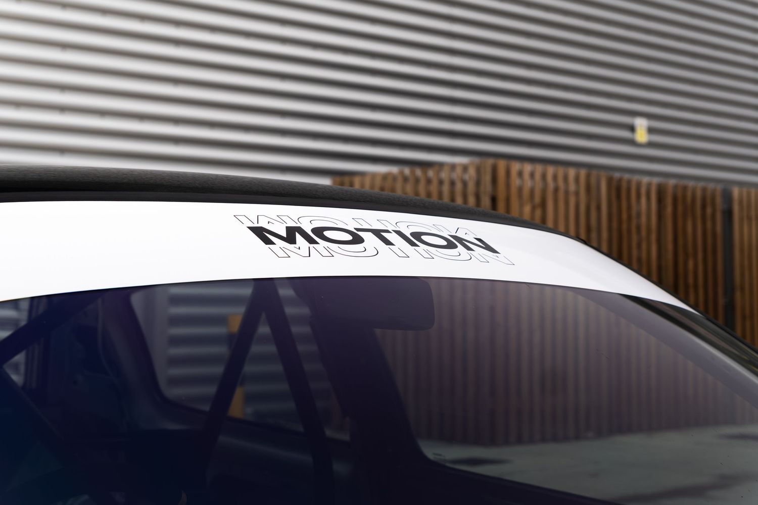 Close-up detail of a white Motion windscreen banner on a black performance car.