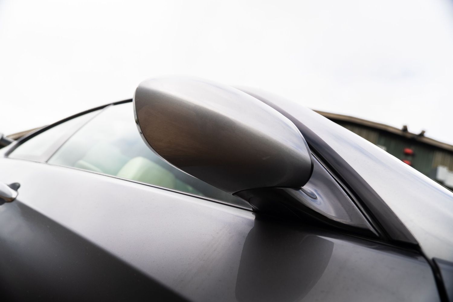 Close-up detail of a dark carbon fibre side mirror on a black BMW sports car.