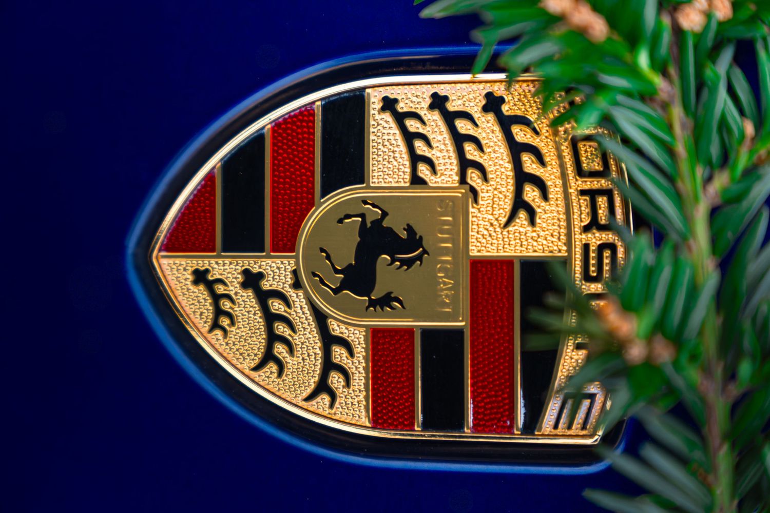 Macro close-up of vintage Porsche crest badge in gold, red, and black with horse emblem detail.