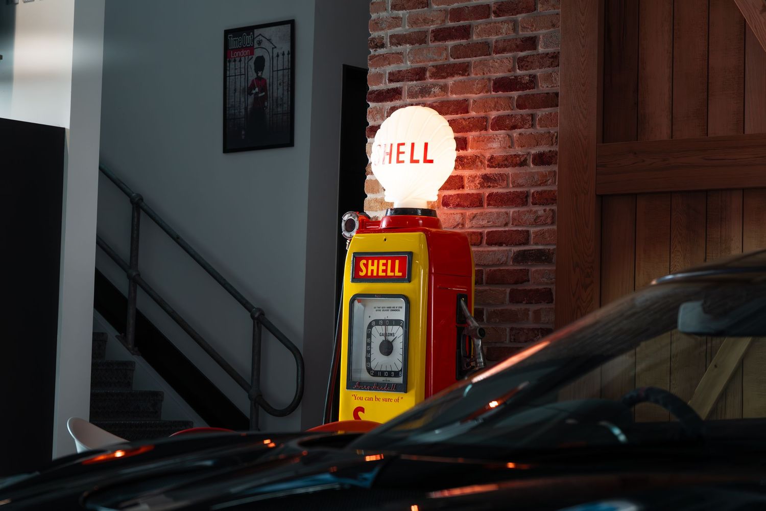 Vintage Shell petrol pump display with illuminated globe sign inside a classic car showroom interior.