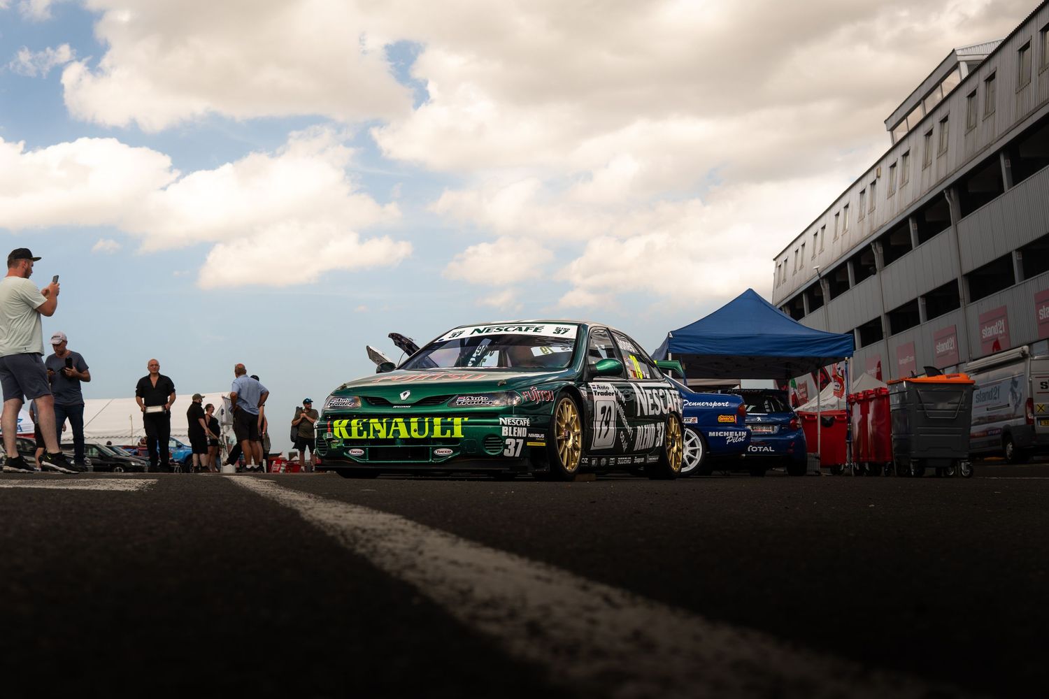 Green and yellow Renault touring car number 51 parked in pit lane at a motorsport event.