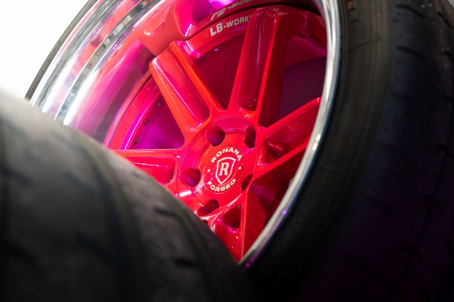 Vivid pink and chrome Rotiform multi-spoke alloy wheel with low-profile tire on a custom car.