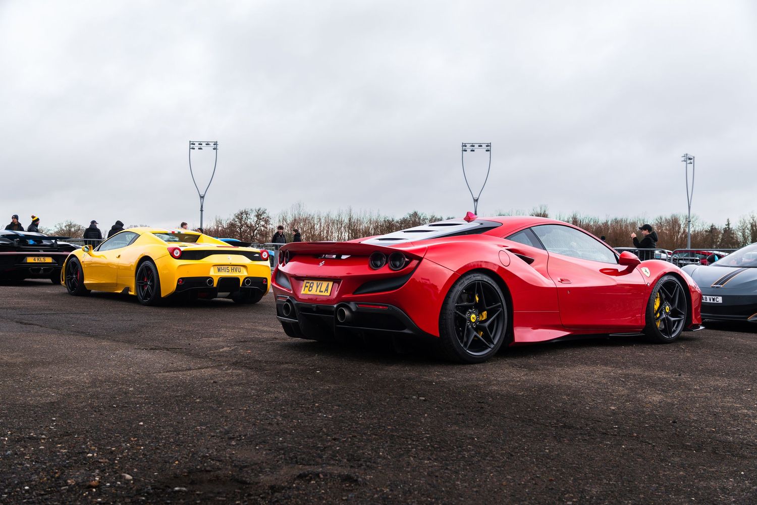 Red Ferrari F8 Tributo and yellow Ferrari 458 at a UK supercar meet.