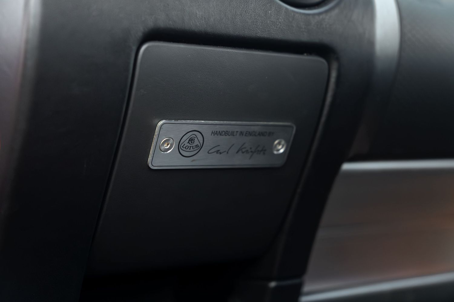 Close-up of Lotus numbered limited edition plaque on dark interior dashboard trim panel.