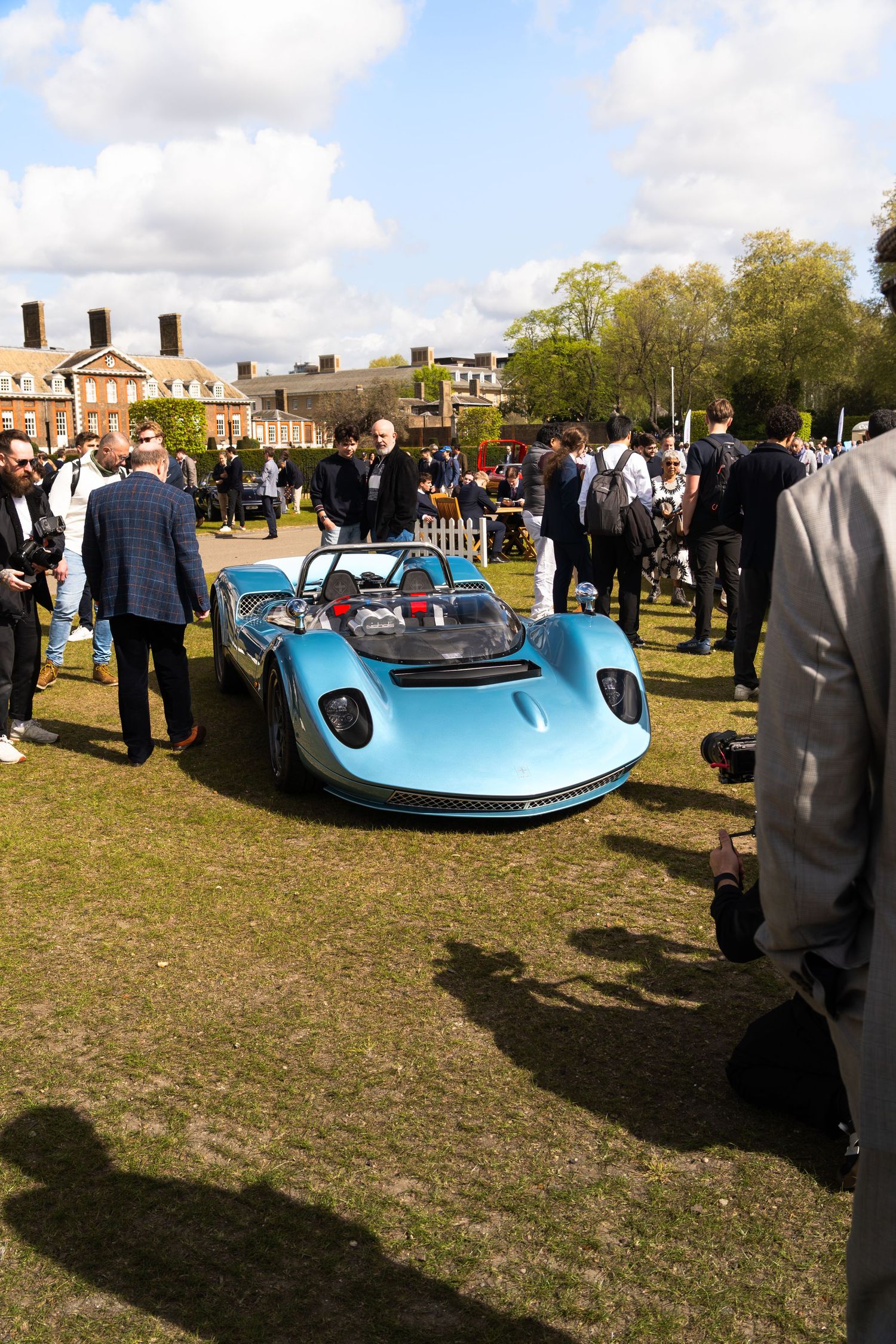 Light blue vintage open-wheel racing car surrounded by spectators at an outdoor car show.