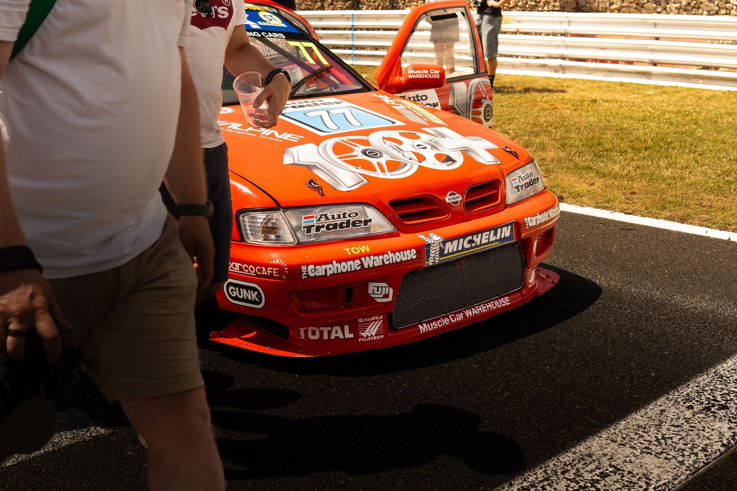 Orange Nissan Primera BTCC race car with Halfords and Michelin sponsors in pit lane at motorsport event.