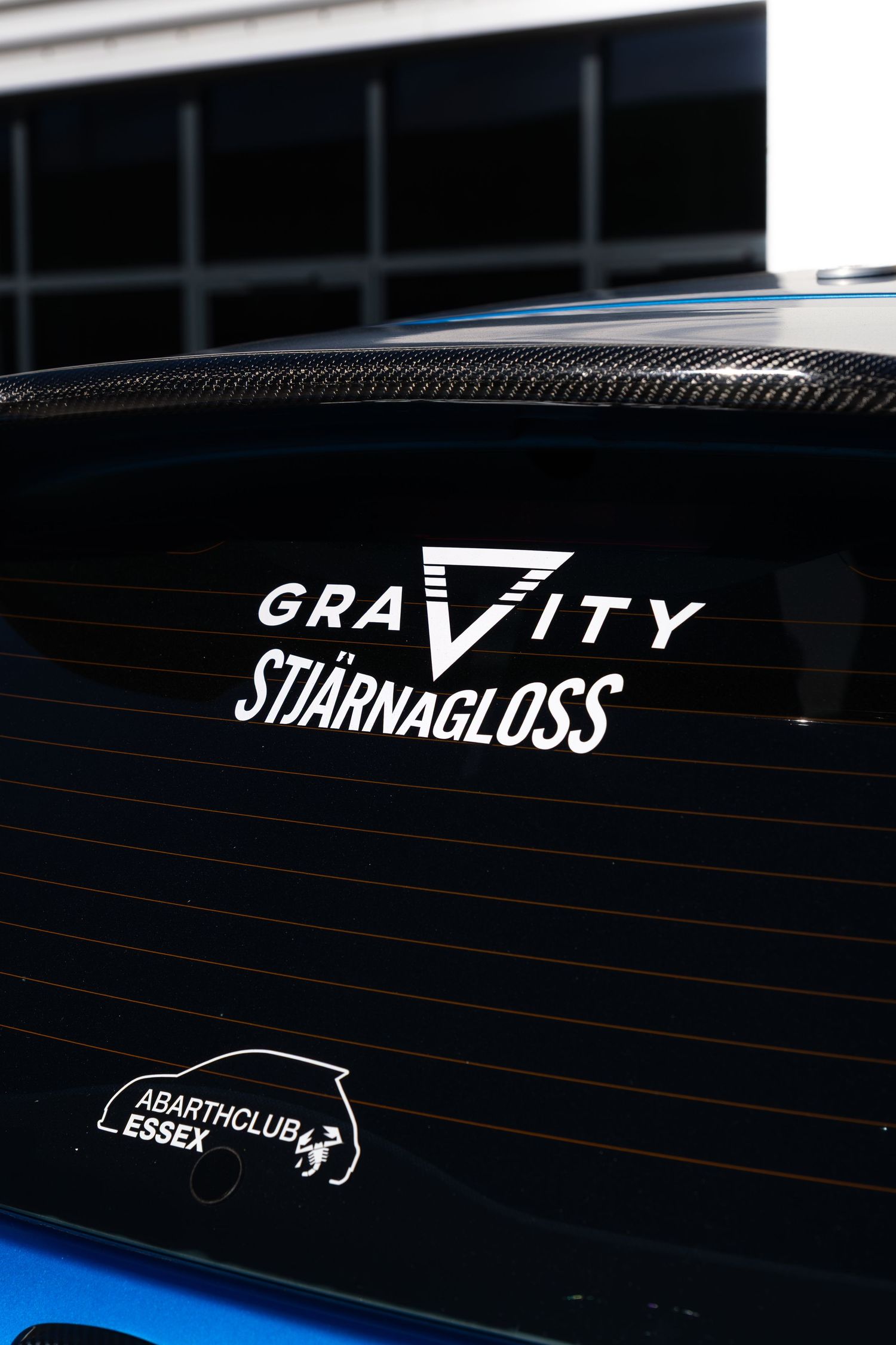 Gravity Stjarnagloss and Abarth Club Essex decals on the rear window of a blue Abarth 595.