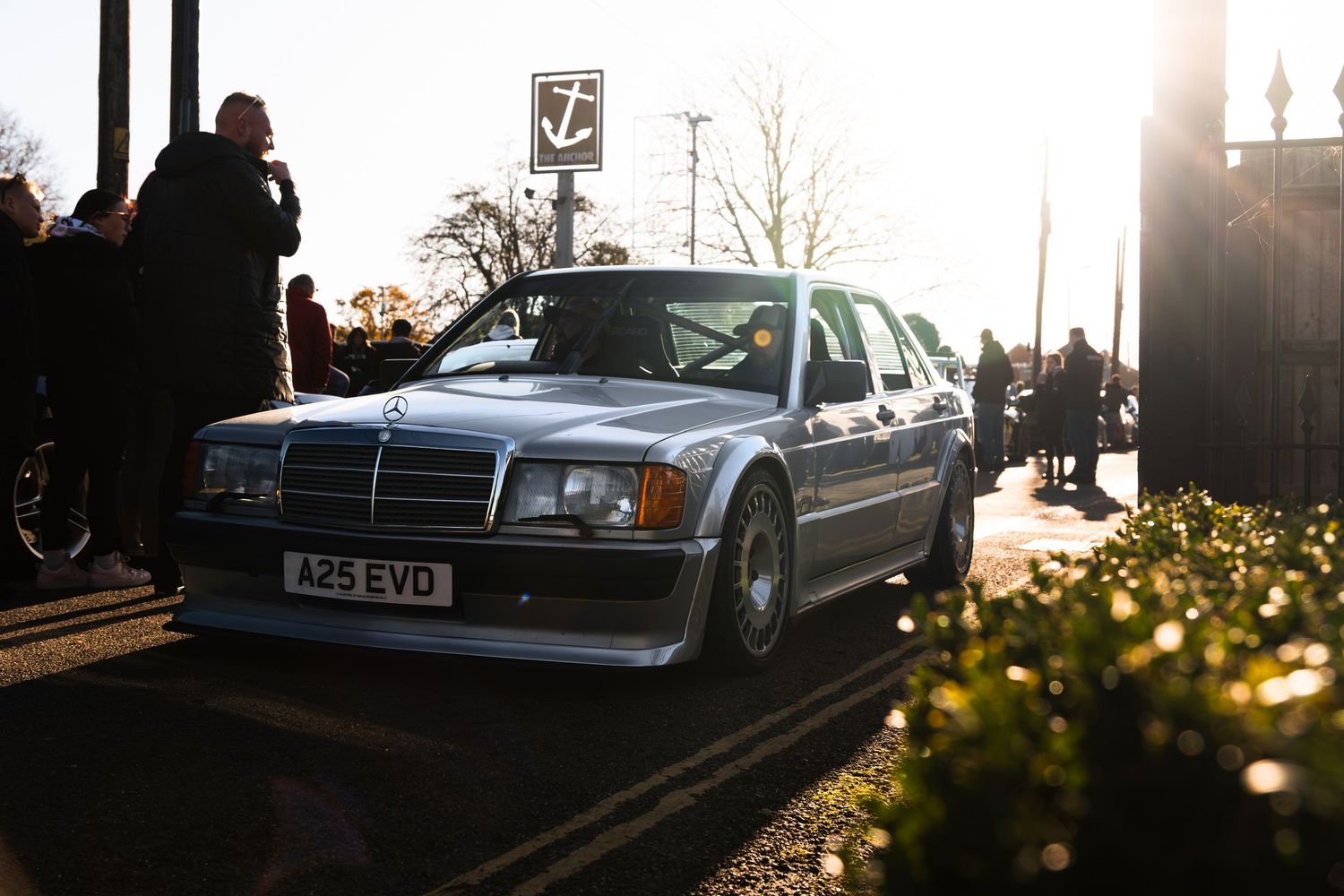 Classic silver Mercedes-Benz 190E with registration A25 EVD driving at a car meet.