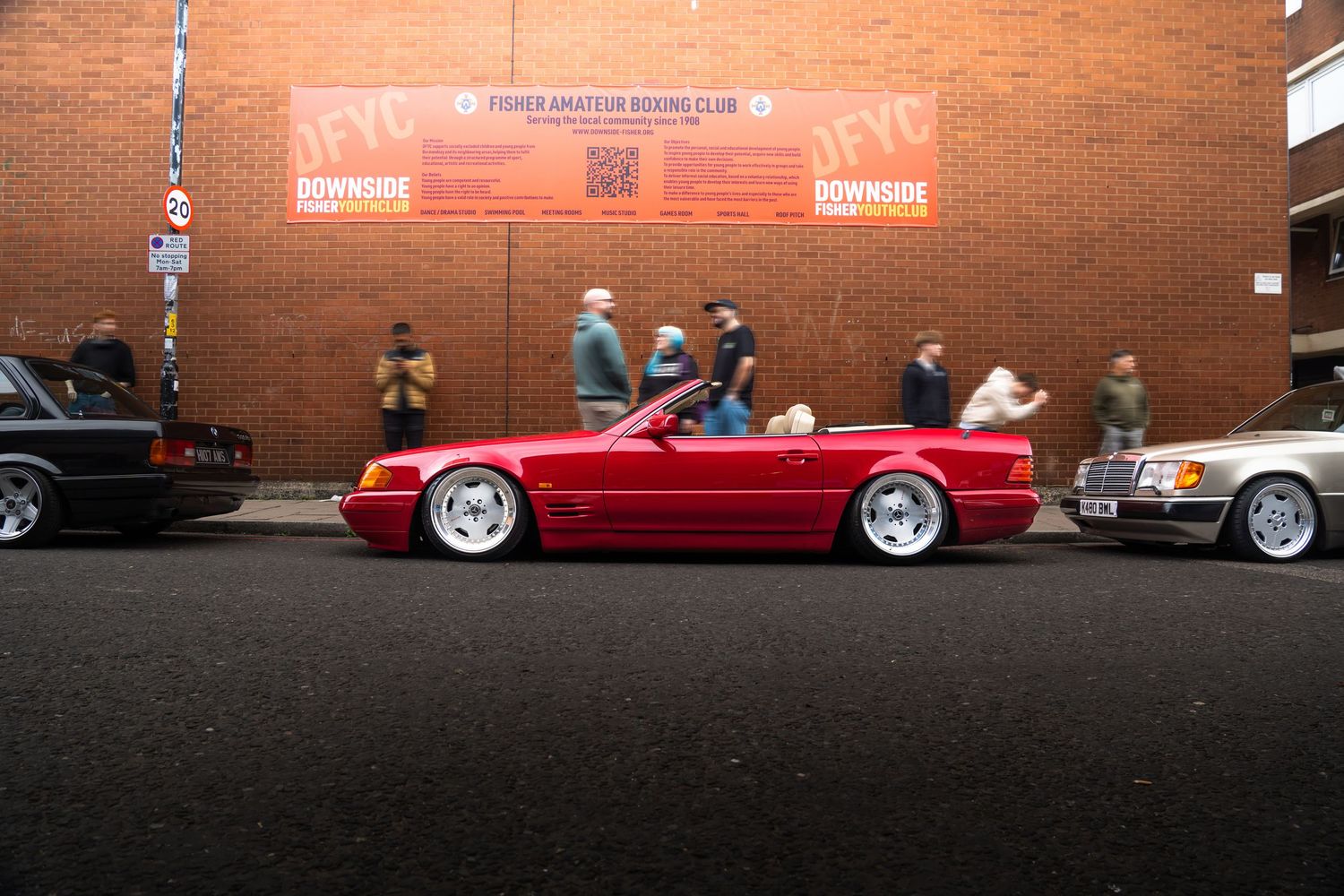 Slammed red Mercedes SL convertible parked outside Fisher Amateur Boxing Club.