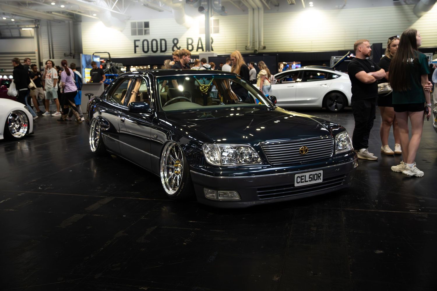 Dark blue lowered Lexus LS400 Celsior on BBS wheels displayed at an indoor car show.