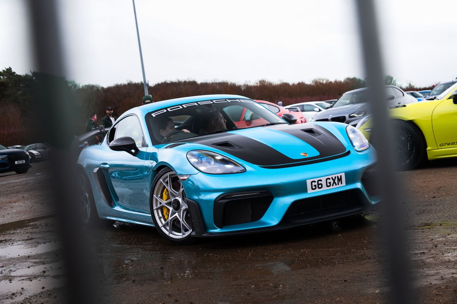 Miami blue Porsche 718 Cayman GT4 with carbon hood at a UK car meet event.